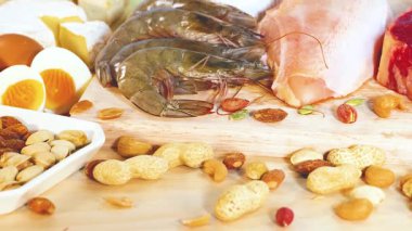 Fındık, deniz ürünleri ve süt ürünleri dahil olmak üzere çeşitli protein zengini gıdaların parlak ışıklandırmalı ahşap bir yüzeyde sergilenmesi.