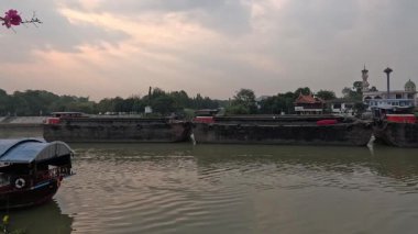 Gün batımında sakin bir nehirde yelken açan tekne.