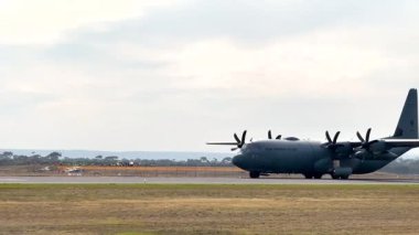 Lockheed Martin C-130J Süper Herkül taksileri Geelong, Avustralya 'daki Avalon Hava Gösterisi' nde bulutlu bir gökyüzü altında pist üzerindedir.