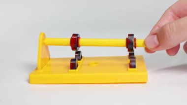 Manyetik halkalı sarı bir çubuk duruş üzerinde çekim ve itme gösterir, kontrollü bir düzende manyetik kuvvetleri vurgular.