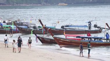 İnsanlar kumlu bir sahilde teknelere yaklaşır.