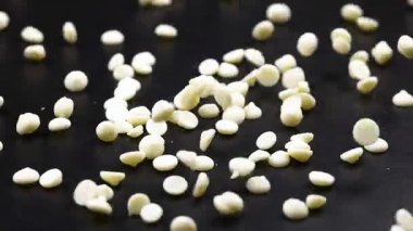 Siyah bir yüzeye saçılmış beyaz çikolata parçaları.