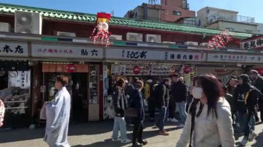 Yürüyen ziyaretçilerin olduğu kalabalık bir pazar caddesi.