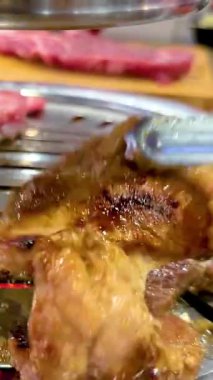 Bangkok 'ta bir lokantada et ızgarası. Tong, cızırdayan eti ızgaraya çevirir.