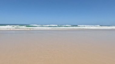 Sakin okyanus dalgaları yavaşça kumlu kıyıya yaklaşıyor