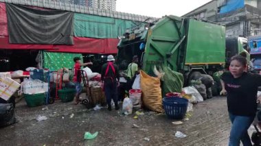 İşçiler çöpleri toplayıp kamyona yüklüyorlar.