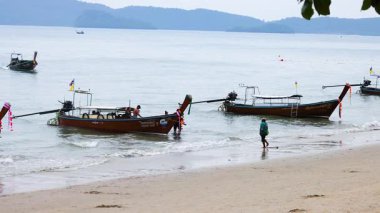 Huzurlu bir sahilde kayıklar ve insanlar