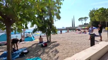 İnsanlar kumsalda güneşli bir günün tadını çıkarıyor.