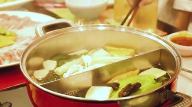 Yemek çubukları güvecin içindeki malzemeleri karıştırıyor.