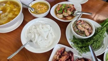Yemek masasında çeşitli Tayland yemekleri sergilenmektedir..