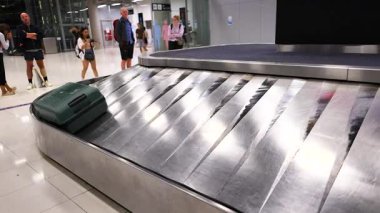 Bangkok 'ta havaalanı bavulu boyunca hareket eden yeşil bir bavul, yakında bekleyen yolcuların beklentilerini yakalıyor.