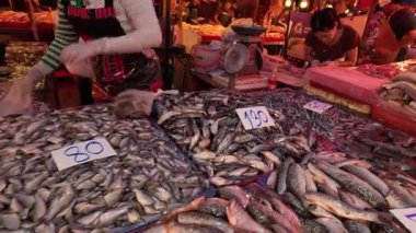 Tedarikçiler kalabalık bir pazarda balık düzenliyor.