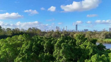 Havadan çekilen görüntüler yemyeşil, dingin bir göl ve parlak mavi gökyüzünün altındaki Altın Sahil siluetini yakalıyor.