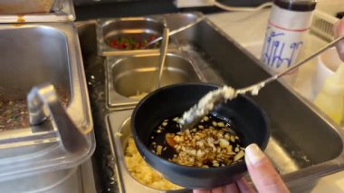 Eller Bangkok mutfağında Kore barbekü sosu hazırlıyor. Malzemeleri sıcak ışık altında hassasiyetle karıştırıyor.