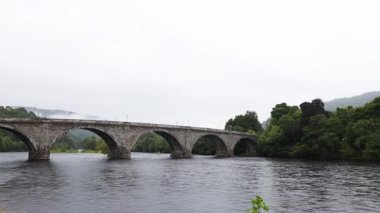 Sakin bir nehir boyunca uzanan taş köprü