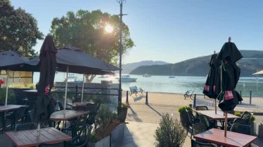 Yeni Zelanda, Akaroa 'da, açık gökyüzü ve canlı güneş ışığıyla açık hava yemek sahnesi.
