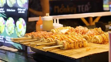 Gece pazarında Japon pizza şişleri pişirmek.