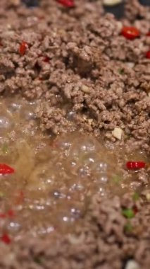 Kabaran soslu kırmızı biber ve baharatla pişirilmiş kıyma. Yakın çekim görüntüsü canlı pişirme sürecini yakalar
