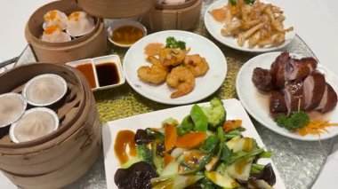 Değişen bir masa üzerinde çeşitli yemek ve sosları vurgulayan canlı bir Çin mutfağı.