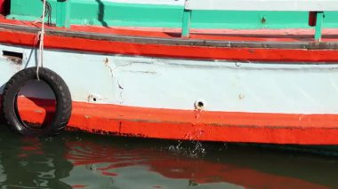 Lastik çamurluğu olan boyalı bir tekne suda yüzer..