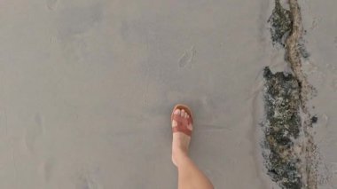 Kumsalda yalınayak yürüyen biri.