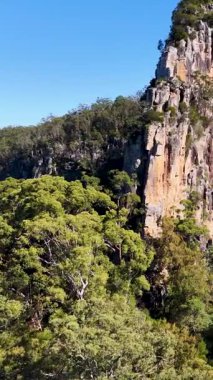 Hava görüntüleri, açık mavi gökyüzünün altında yemyeşil yemyeşil ile çevrili görkemli Nimbin Kayalarını yakalıyor.
