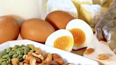 Yumurtalar, fındıklar, süt ürünleri ve etler de dahil olmak üzere çeşitli protein zengini yiyecekler iyi aydınlatılmış bir ortamda sanatsal olarak düzenlenmiştir.