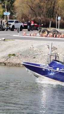 Yeni Zelanda, Glenorchy 'deki göl kıyısındaki bir rıhtıma gün ışığında bir sürat teknesi yanaşır ve yanaşır.