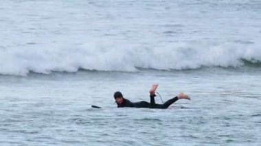 Sörfçü okyanusta kürek çekiyor ve dalgaları yakalıyor