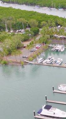 Hava görüntüleri Port Douglas marinasında, yemyeşil ve yumuşak gün ışığında sakin sularla çevrili yatları yakalıyor.