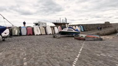 Tekneler yanaşıyor ve insanlar limanda yürüyor.