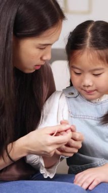 Bir anne ve kız kapalı, odaklanmış bir aktiviteye girişir. Kapalı bir ortamda, yumuşak ışıklandırmalı.