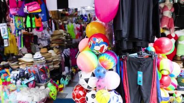 Şapkaları, kıyafetleri ve oyuncakları olan canlı bir dükkan.