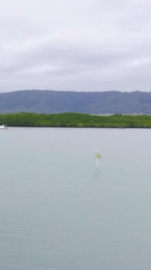 Yelkenliler sakin sularda, Avustralya, Port Douglas 'ta bulutlu gökyüzünün altında, sakin ve huzurlu bir manzara yaratarak zarifçe ilerler.