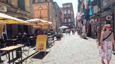 Napoli caddesinde insanlar yürüyor ve alışveriş yapıyor.