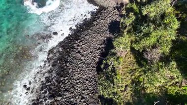 Dalgalar kayalık kıyı şeridine çarpar ve yemyeşil olur.