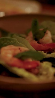 Marul yaprakları üzerinde karides Miang Kham 'ın yakın plan çekimi, loş ışık, canlı renkleri ve dokuları vurguluyor