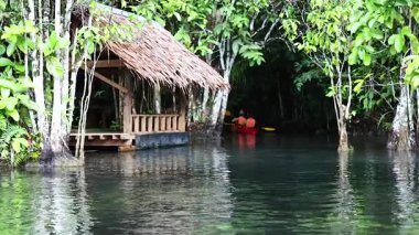 Kayakçılar sakin sularda kırsal bir kulübede gezinirler.