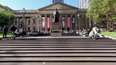 Redmond Barry heykelinin yanında dinlenen insanlar