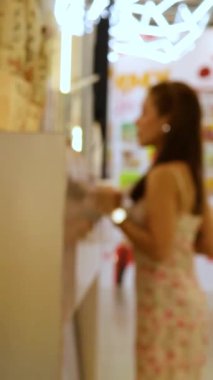 Çiçekli elbiseli bir kadın Bangkok 'ta parlak ışıklı bir büfeden meyve suyu sipariş ediyor. Atmosfer canlı ve renkli.