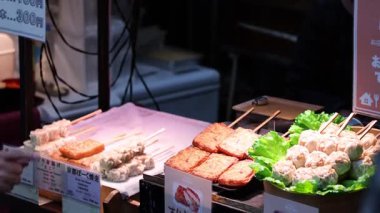 Satıcı gece pazarında şiş yiyecek satıyor.