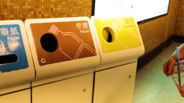 Kişi plastik bardağı geri dönüşüm kutusuna atar.