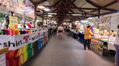 Müşteriler kalabalık bir pazarda tezgahlara bakıyorlar.