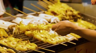 Pazarda ızgara kalamar şiş seçen eller.