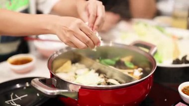 Eller güveç kabına malzeme ekliyor.