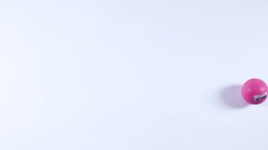 Pembe bir top pürüzsüz bir şekilde yüzeye yuvarlanır.