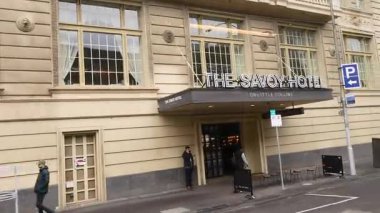 Savoy Oteli 'nin yakınından geçen yayalar.