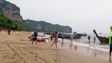 Manzaralı bir sahilde insanlar ve tekneler