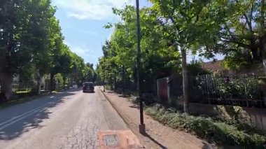 Piedmont 'ta ağaçlarla kaplı bir caddeyi izleyen bir araba var.