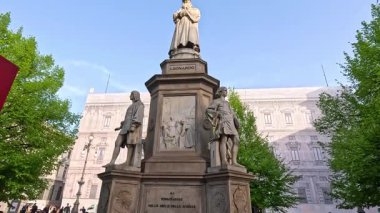 Yeşillik ve insanlarla çevrili bir heykel.